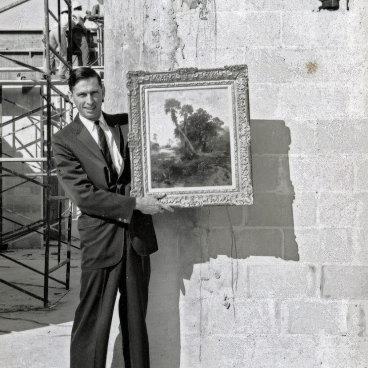 Museum of Fine Arts, St. Petersburg History - Image of man, Rexford Stead, holding a painting of Florida landscape